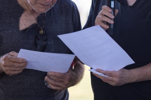 שני אנשים ממשפחת הנפטר, עם חולצה שחורה עם קרע, אבלים וקוראים הספד בבית העלמין האזרחי "בשביל מנוחה נכונה" בראשון לציון.